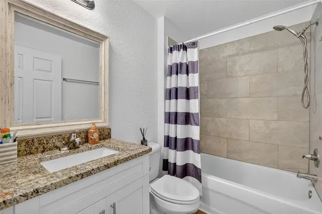 a bathroom with a granite countertop bathtub shower sink and toilet