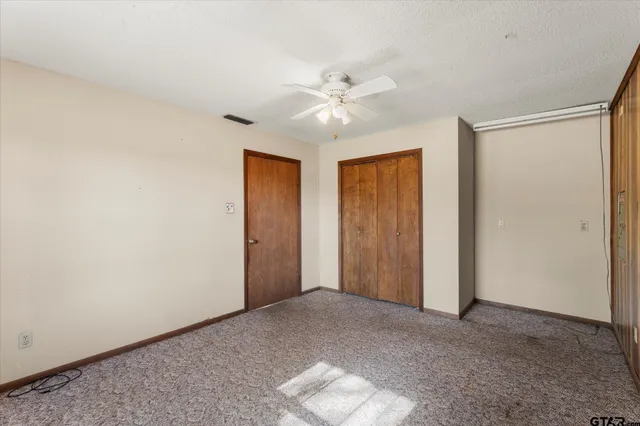 an empty room with a ceiling fan and window