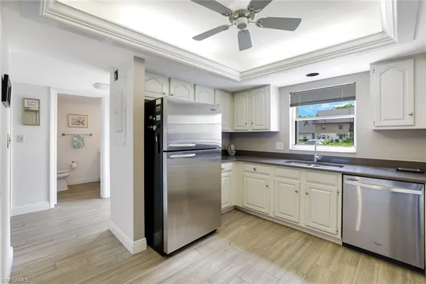 a kitchen with stainless steel appliances granite countertop a refrigerator a sink and white cabinets