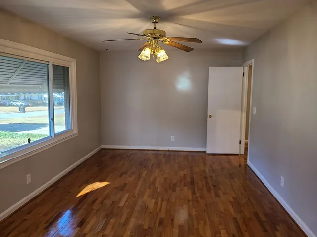 a view of an empty room with window and wooden floor