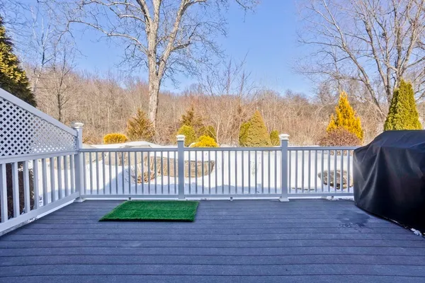 a view of a deck with large trees and wooden fence