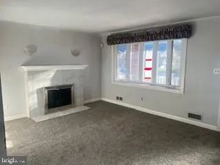 an empty room with windows and fireplace