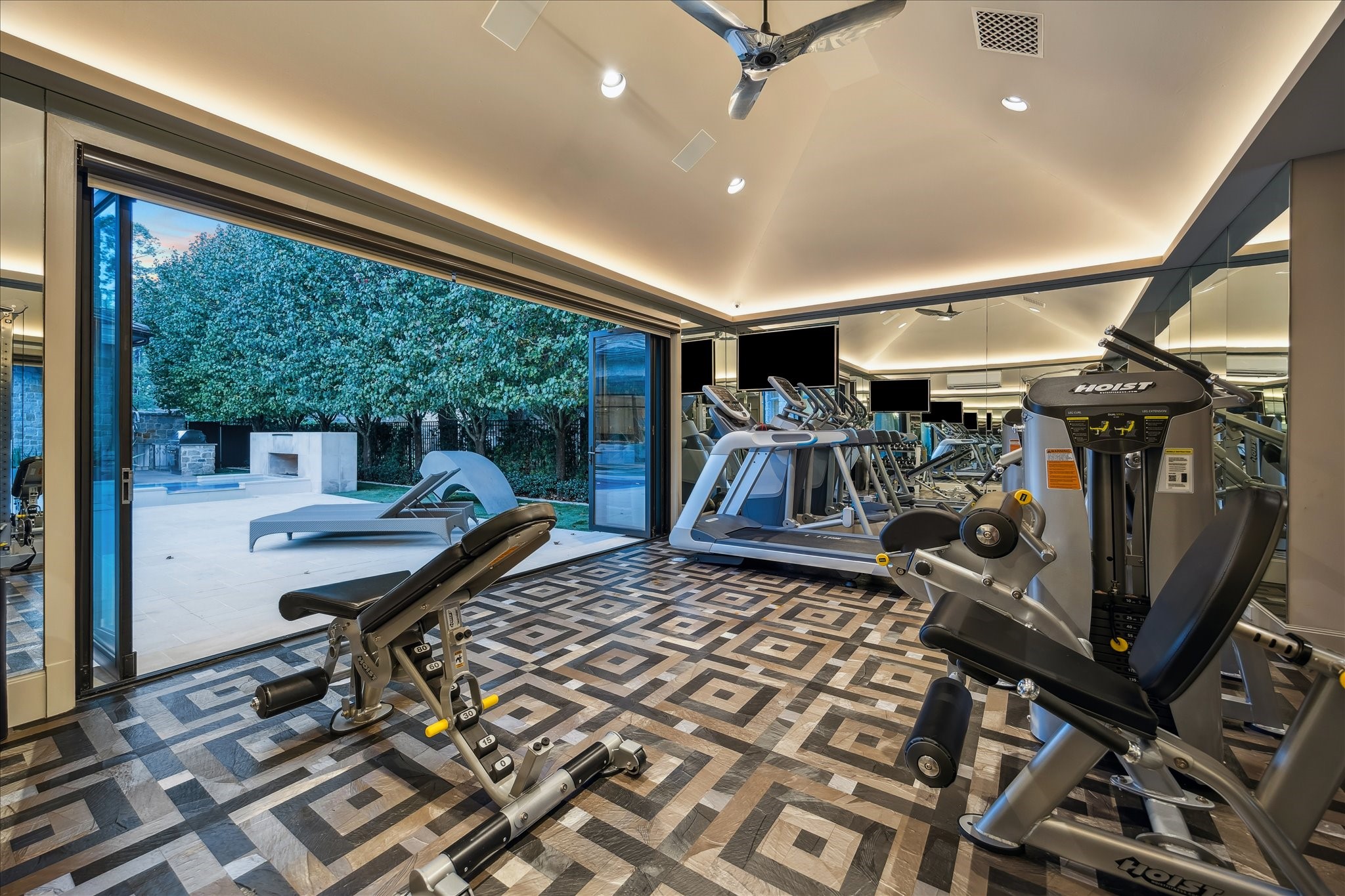 220 Merrie Way Lane Houston, TX 77024 - Photo 44 of 50 A striking fitness space with 12'2" ceilings, floor-to-ceiling mirrored walls, custom flooring, and stacking doors that open directly to the pool.