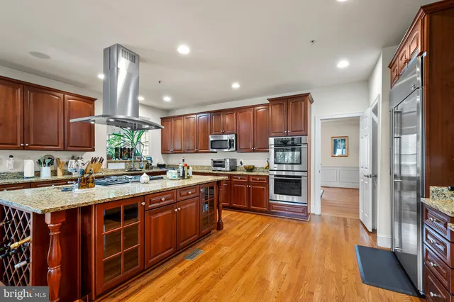a kitchen with stainless steel appliances granite countertop a table chairs and a refrigerator