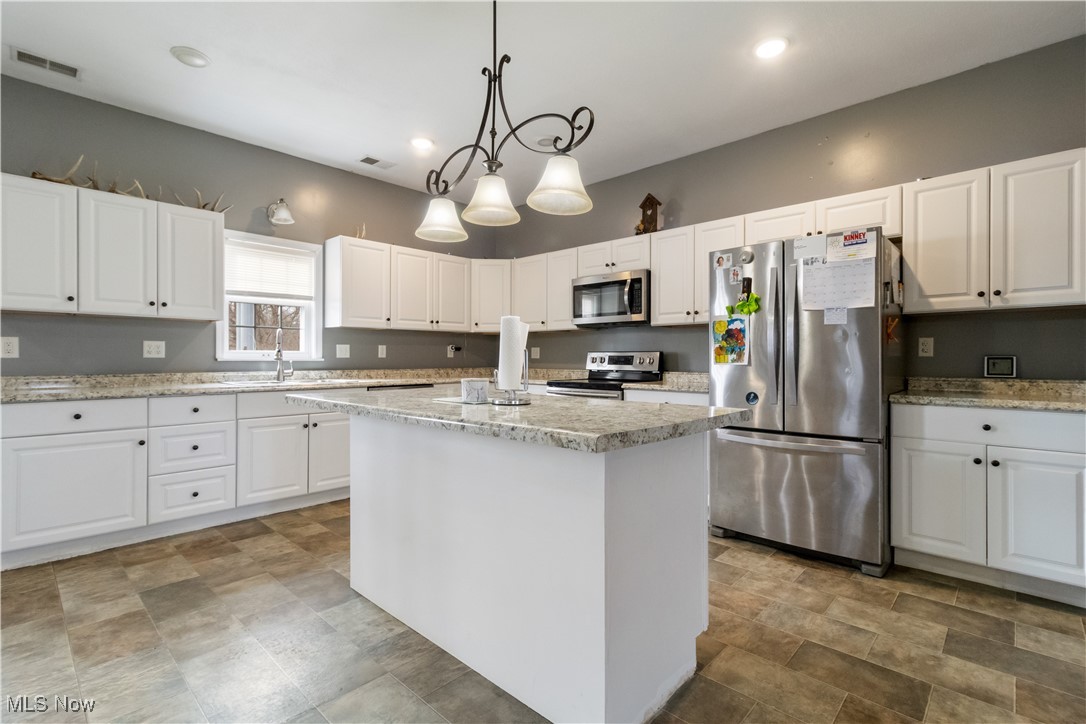 57459 Shry Road Barnesville, OH 43713 - Photo 4 of 44 Kitchen featuring appliances with stainless steel finishes, white cabinetry, pendant lighting, light stone counters, and a center island