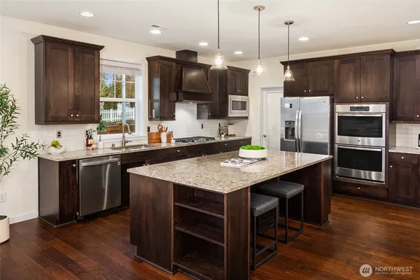 a kitchen with kitchen island granite countertop a sink appliances and wooden floor