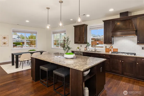 a kitchen with stainless steel appliances granite countertop a kitchen island a stove a table and chairs