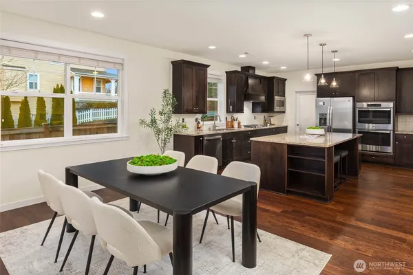 a dining room with stainless steel appliances kitchen island granite countertop a dining table and chairs