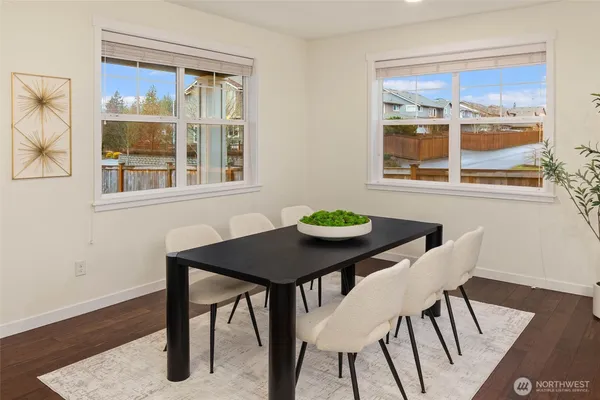 a view of a dining room with furniture a rug and wooden floor