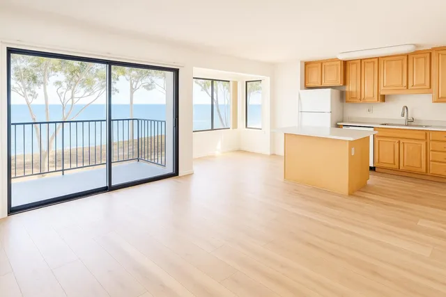 a view of a kitchen with kitchen island a sink wooden floor and a large window