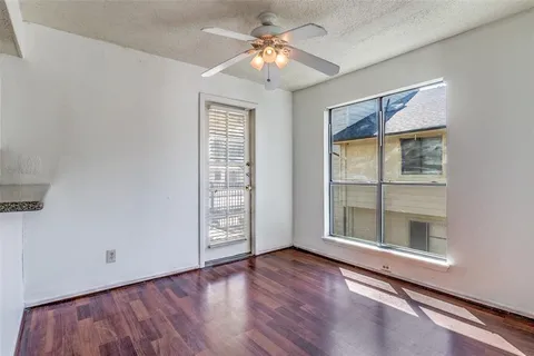 an empty room with wooden floor chandelier fan and windows
