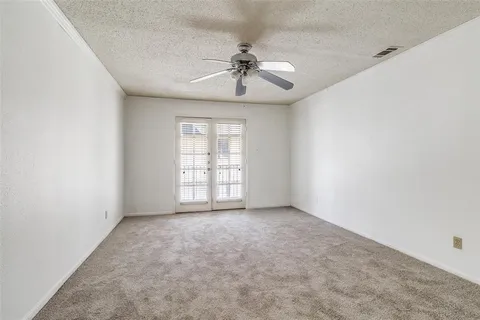 an empty room with a chandelier fan and windows