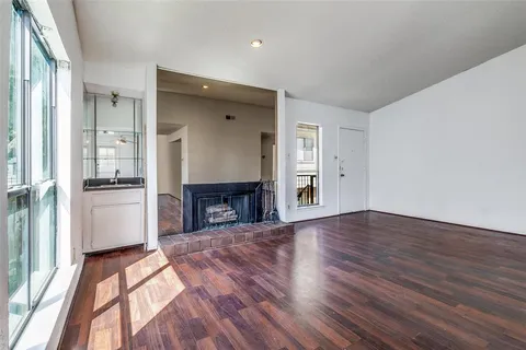 an empty room with wooden floor fireplace and windows