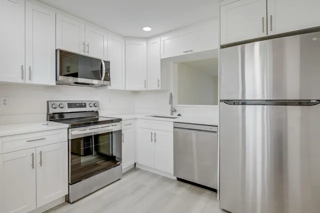 a kitchen with white cabinets and white appliances