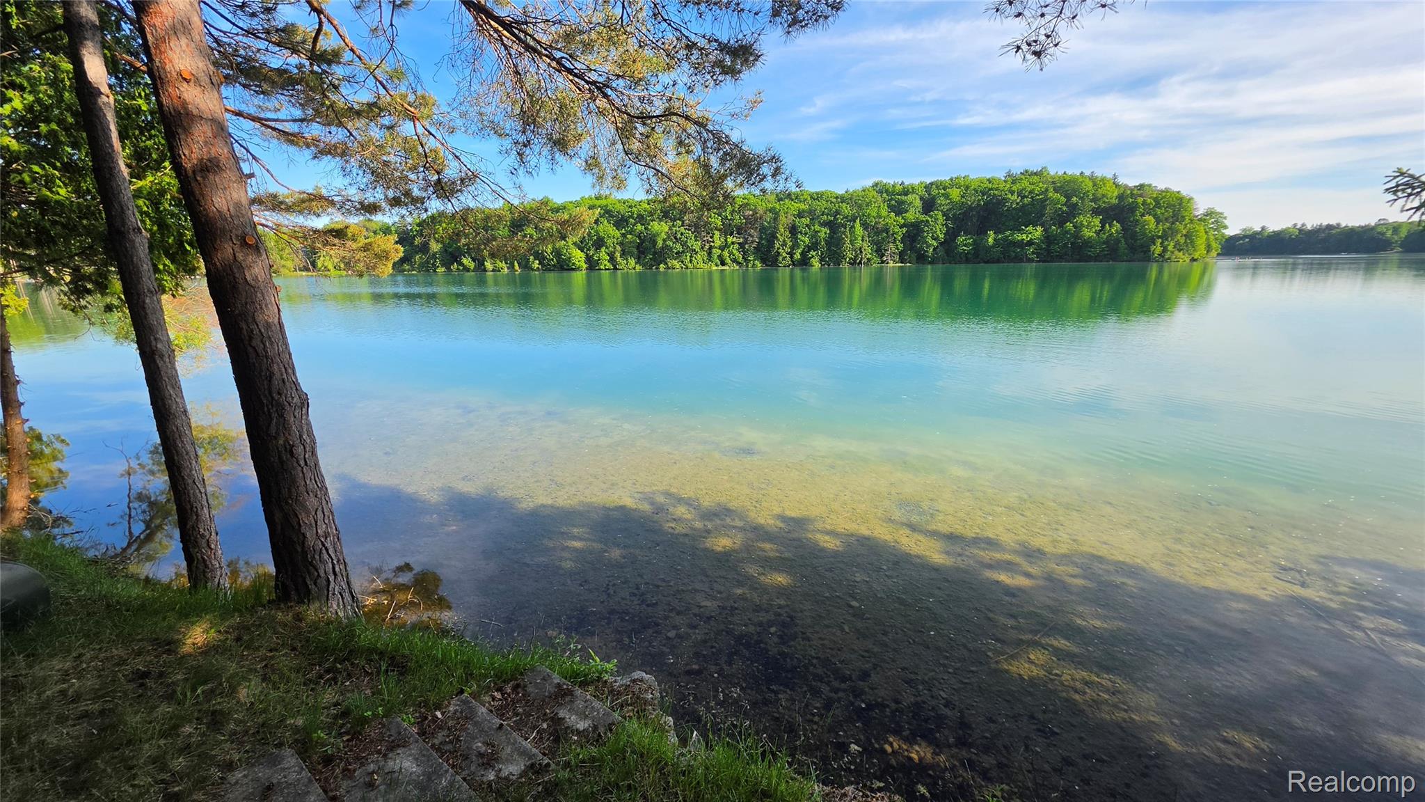Expansive waterfront with clear, blue-green water and a visible sandy bottom
