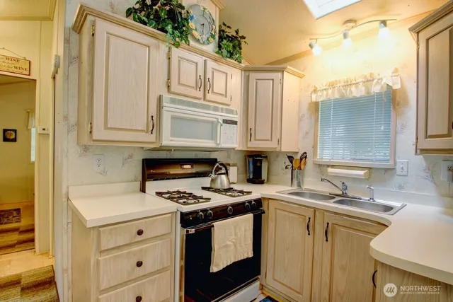 a kitchen with granite countertop a sink a stove and cabinets