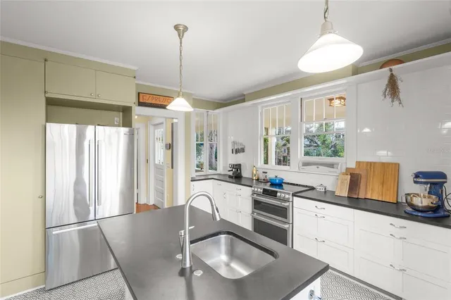 a kitchen with stainless steel appliances granite countertop a stove a sink a refrigerator a center island a dining table and chairs