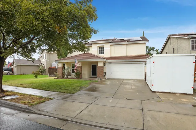 a view of a house with a yard and large tree
