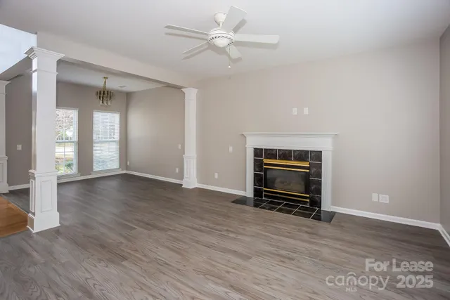 an empty room with wooden floor a ceiling fan and windows