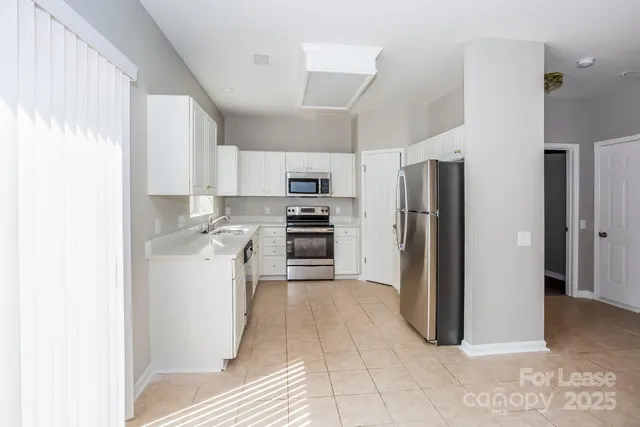 a kitchen with a refrigerator a stove top oven and cabinets