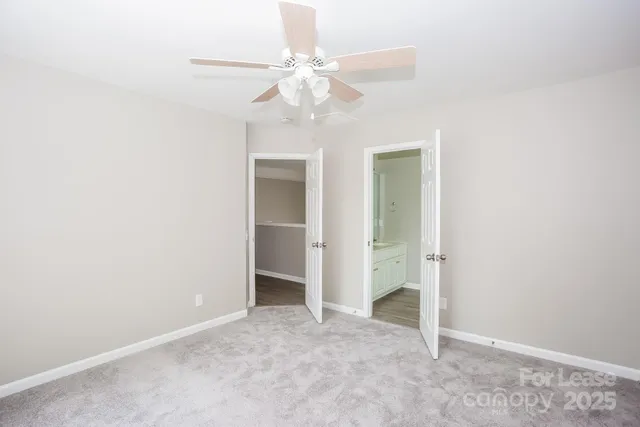 an empty room with a chandelier fan and closet