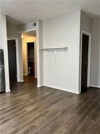 a view of an empty room with wooden floor and a closet