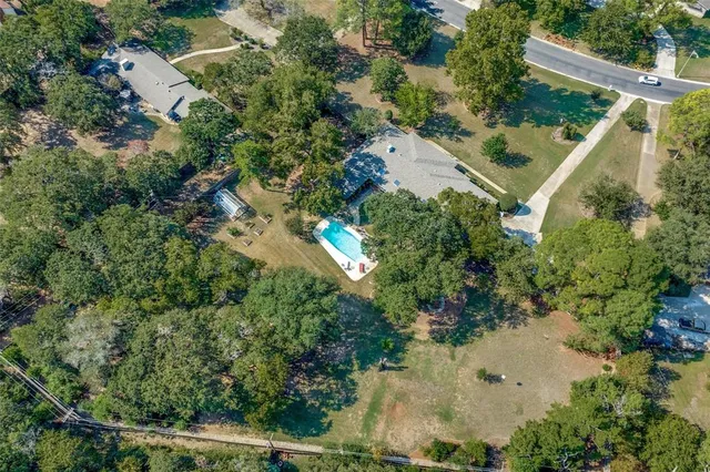 an aerial view of residential house with outdoor space and trees all around