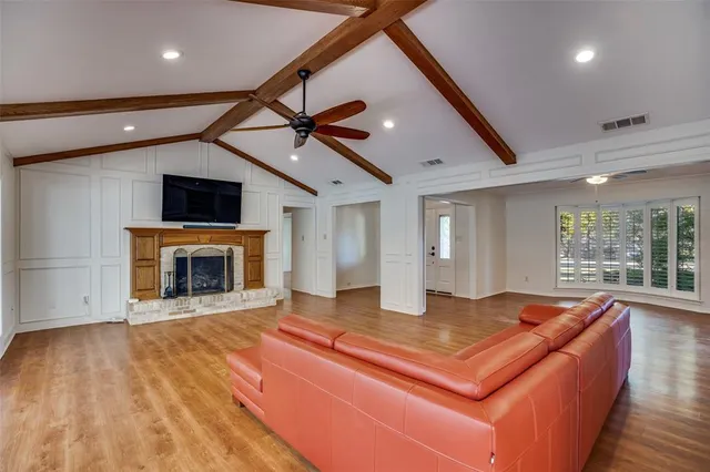 a living room with stainless steel appliances furniture a fireplace and a flat screen tv