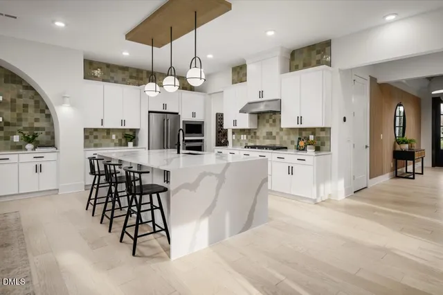 a kitchen with stainless steel appliances kitchen island granite countertop a sink and a refrigerator