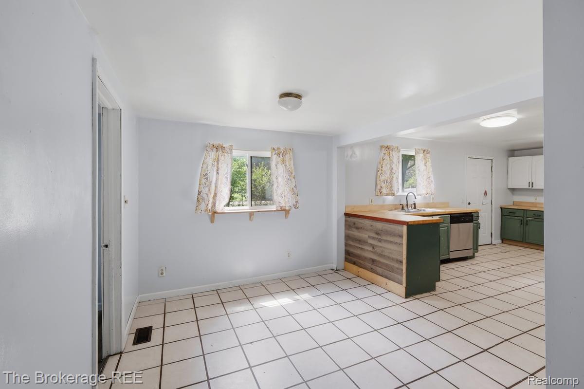 10135 Clark Road Davison, MI 48423 - Photo 19 of 38 Open-concept kitchen featuring an island with wood-finish paneling, green cabinetry, stainless steel appliances, and tile flooring