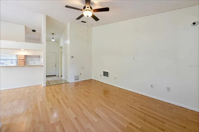 a view of empty room with wooden floor and fan