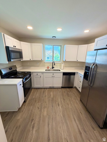 450 13800 South, Unit 2 Draper, UT 84020 - Photo 5 of 21 Modern kitchen featuring wood-finish flooring, white cabinetry, integrated stainless steel appliances, a window with exterior views, and recessed ceiling lighting