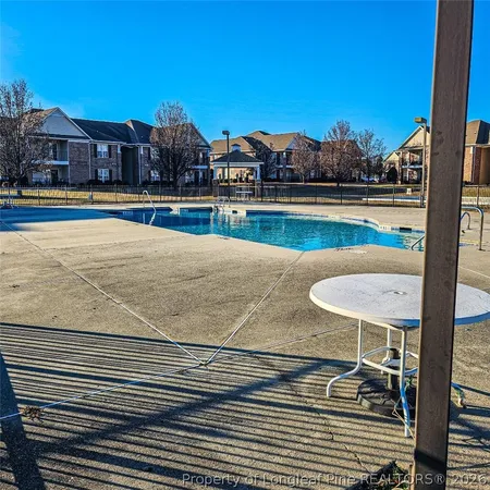 a view of a swimming pool with a lawn chairs under an umbrella next to a yard
