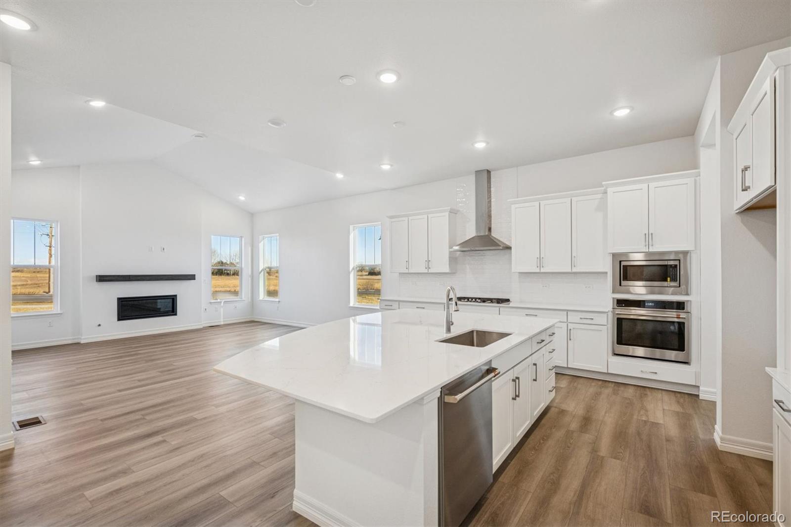 1162 Weller Street Timnath, CO 80547 - Photo 5 of 29 a kitchen with stainless steel appliances granite countertop a kitchen island a stove a sink a refrigerator and white cabinets with wooden floor