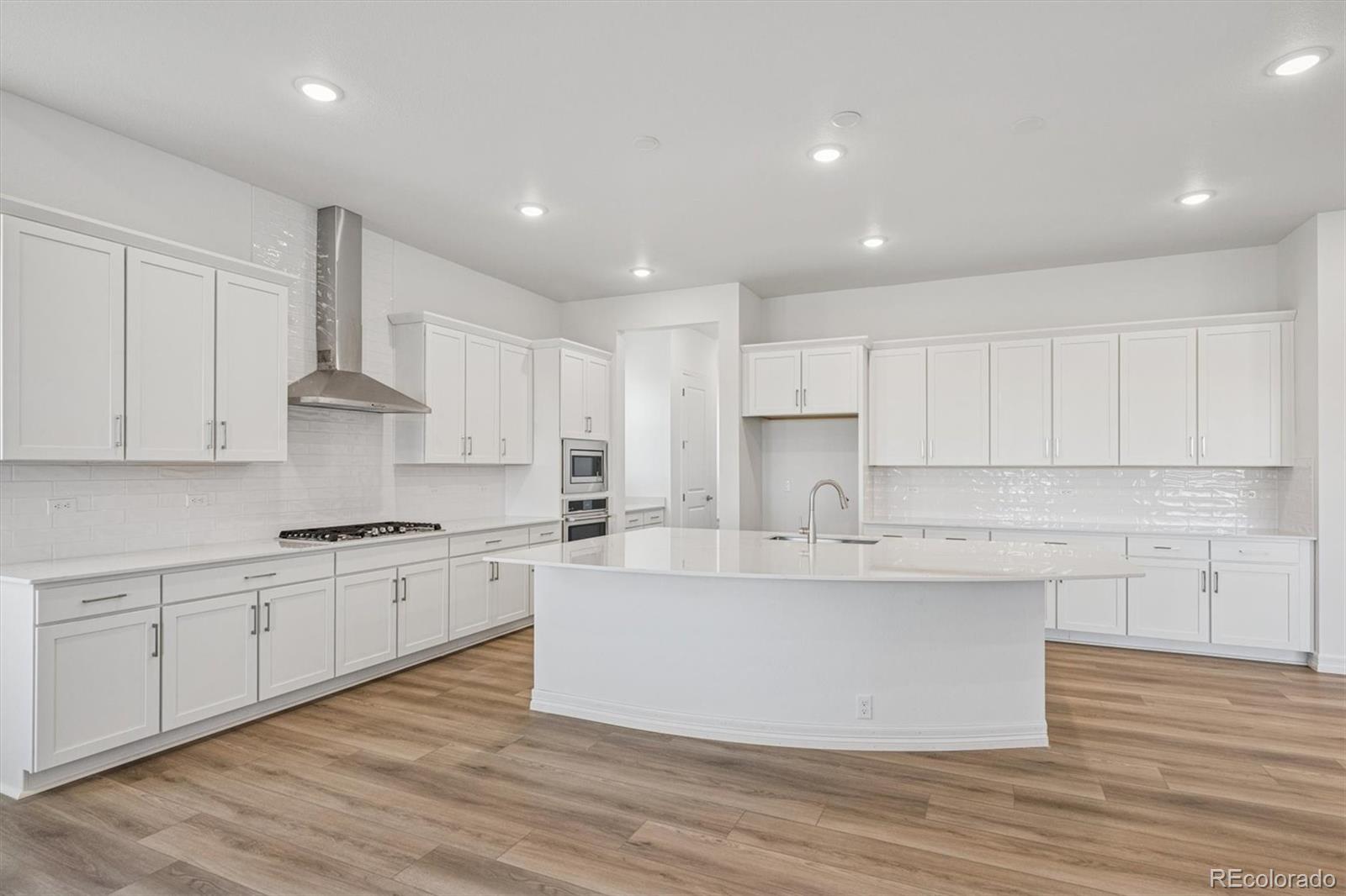 1162 Weller Street Timnath, CO 80547 - Photo 7 of 29 a large kitchen with stainless steel appliances granite countertop a stove a sink dishwasher and white cabinets with wooden floor