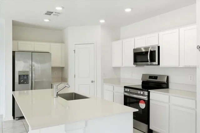 a kitchen with stainless steel appliances a refrigerator a stove a microwave a sink and cabinets