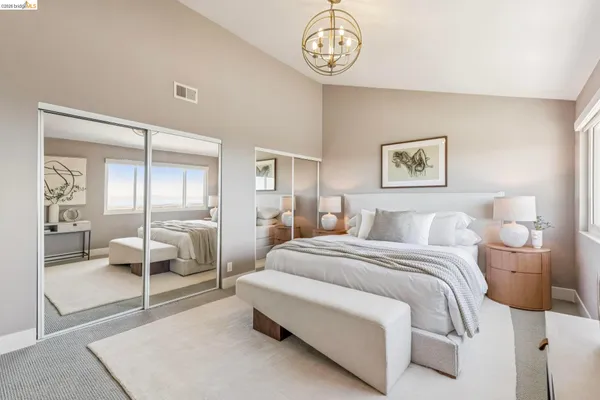 a spacious bedroom with a bed a table and painting