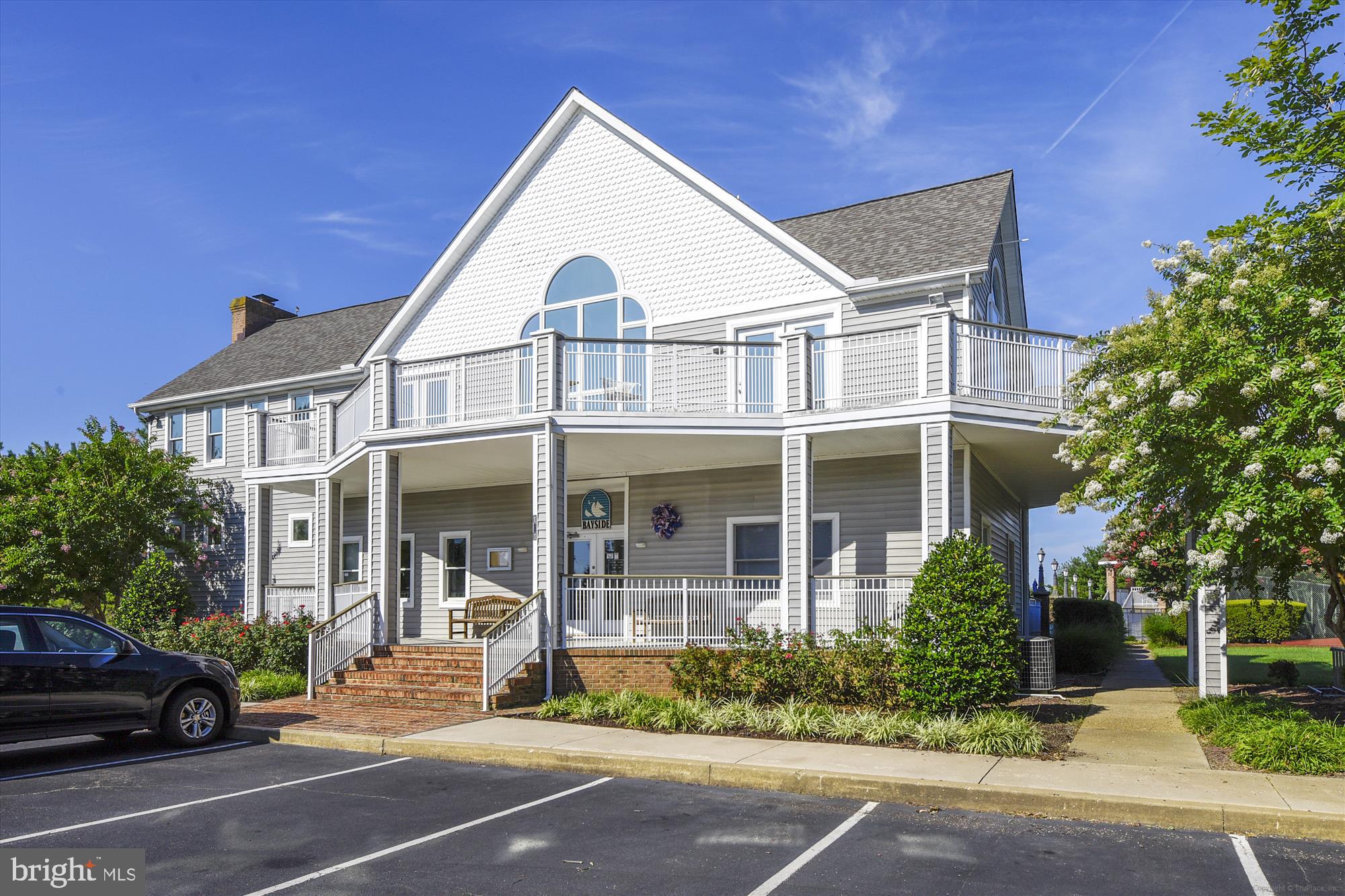 106 Bodys Neck Road Chester, MD 21619 - Photo 12 of 17 a view of a white house with large windows and a table and chairs under an umbrella