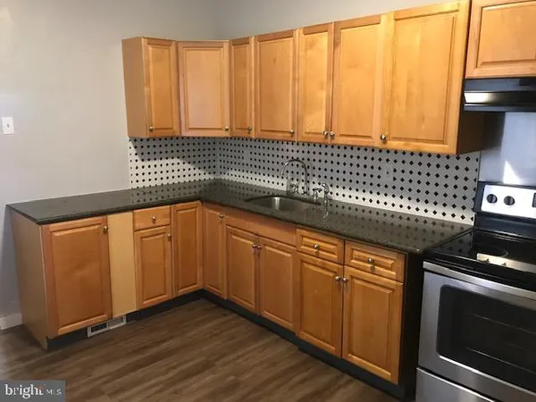 a kitchen with granite countertop wooden cabinets a sink and a stove