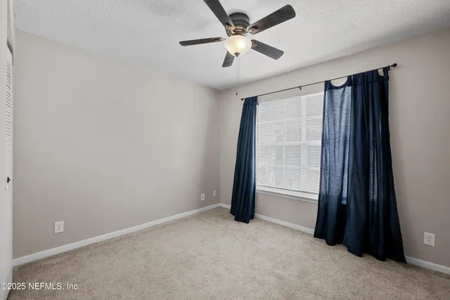 an empty room with closet and a ceiling fan