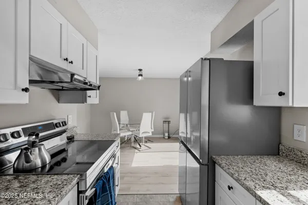 a kitchen with granite countertop a sink a stove and refrigerator