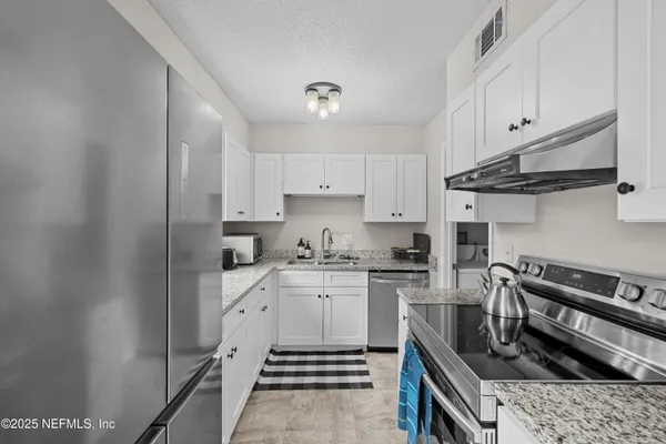 a kitchen with stainless steel appliances granite countertop a stove a sink and a refrigerator