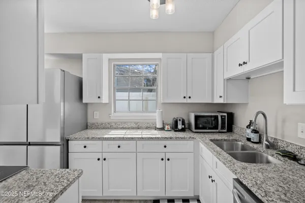 a kitchen with granite countertop a sink a stove and cabinets