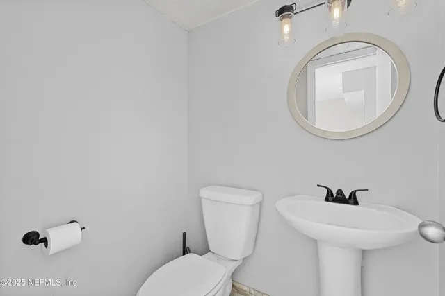 a bathroom with a toilet a sink and mirror