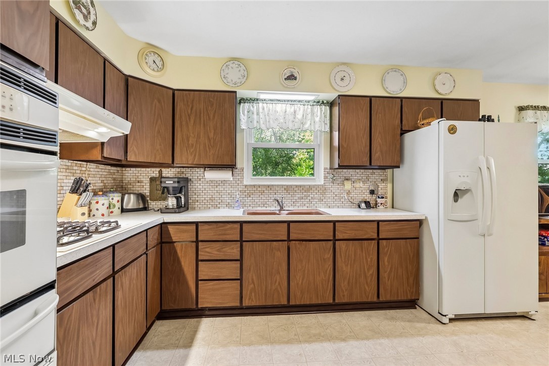 2428 Antioch Road Perry, OH 44081 - Photo 23 of 46 Functional kitchen featuring extensive wood-finish cabinetry, white countertops, and a full tile backsplash