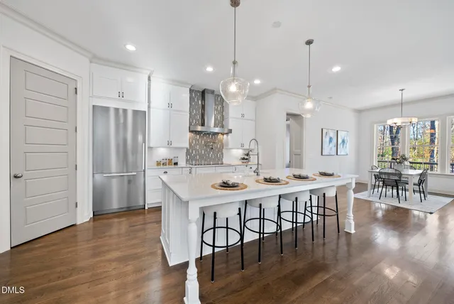 a kitchen with stainless steel appliances a dining table chairs stove refrigerator and cabinets