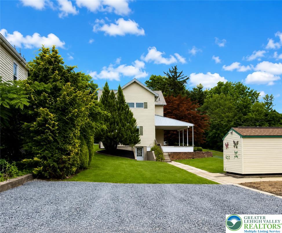 5540 Main Street Whitehall, PA 18052 - Photo 52 of 53 A well-maintained residence with a covered porch and a detached storage shed set amidst green landscaping.