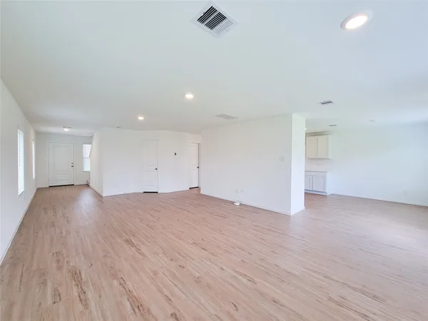 a view of empty room with wooden floor and window