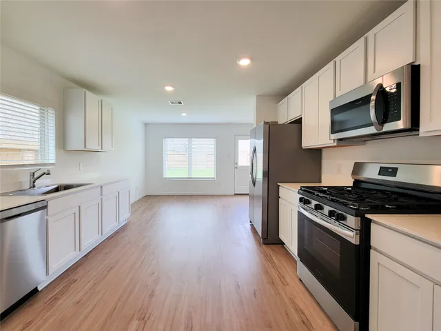 a kitchen with stainless steel appliances granite countertop a stove a sink and a microwave