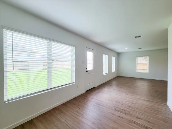 a view of an empty room with wooden floor and window